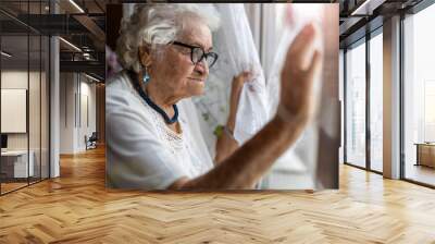 Senior woman looking out of window at home
 Wall mural