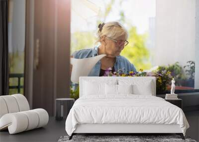 Senior woman taking care of her plants on the balcony
 Wall mural