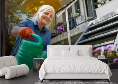 Senior woman watering plants in her garden
 Wall mural