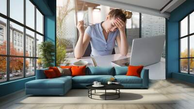 Tired, stressed businesswoman at laptop in office Wall mural