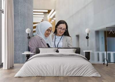 Two female co-workers using tablet in an office building
 Wall mural