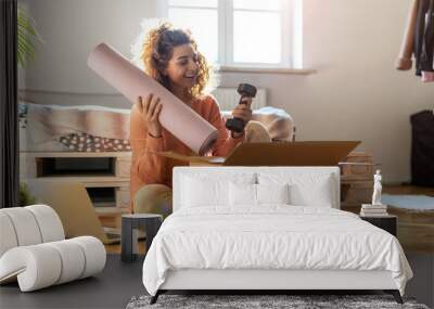 Woman unpacking box with workout equipment at home 
 Wall mural