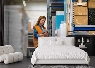 Woman with tablet in factory storehouse checking location of goods Wall mural