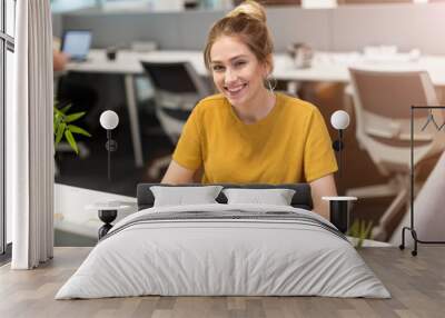 Young business woman working on laptop in office Wall mural