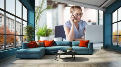 Young business woman working on laptop in office Wall mural