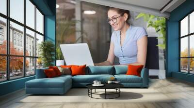 Young business woman working on laptop in office Wall mural