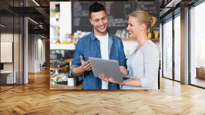 Young cafe owners looking at laptop Wall mural