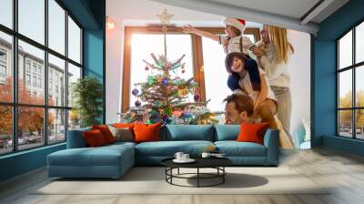 Young family having fun decorating Christmas tree
 Wall mural