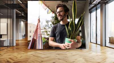 Young man taking care of his plants on a balcony
 Wall mural