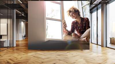 young woman sitting on window sill Wall mural