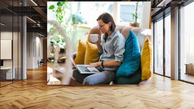 Young woman using a laptop at home
 Wall mural