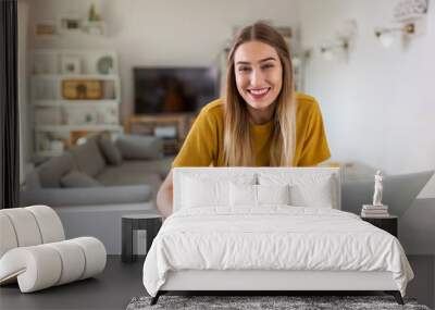 Young woman using her laptop at home  Wall mural