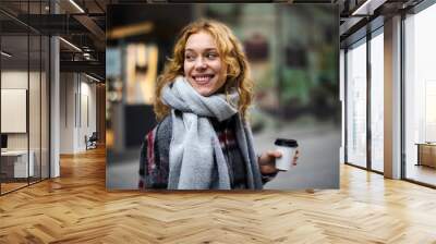 Young woman with coffee cup smiling outdoors
 Wall mural