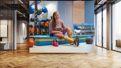 Young woman with prosthetic legs exercising at physiotherapy center
 Wall mural