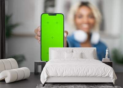 Happy smiling black student girl showing smartphone with green screen.Mockup. Application promotion.online podcast,music,e-learning Wall mural