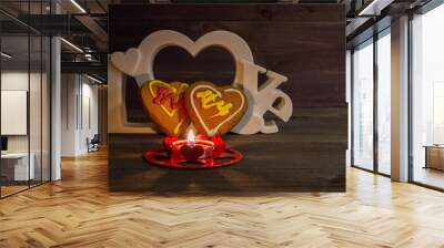 Two heart shaped cookies, a red candle and the word love on a wooden table on Valentine's Day Wall mural