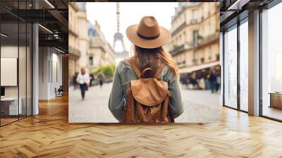 Back view of happy woman with hat and backpack enjoying vacation in Paris Wall mural