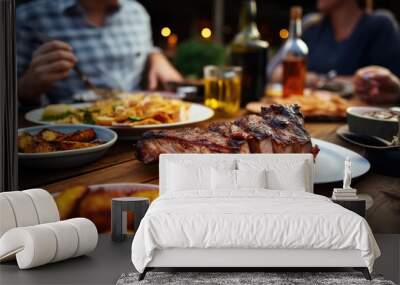 People enjoying a delicious meal, grilled pork ribs with roasted potatoes while dining out Wall mural