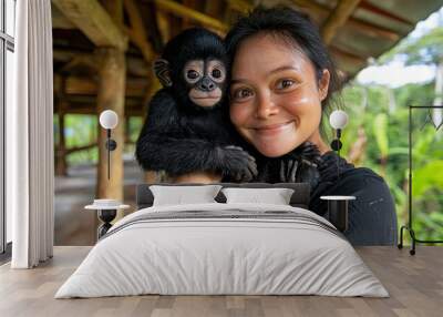 Woman holding cute baby monkey in tropical rainforest Wall mural