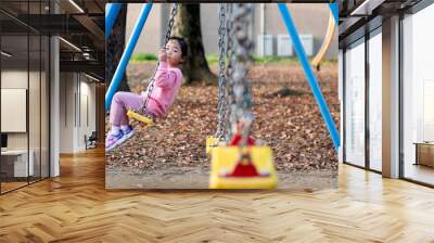 Little girl playing on the swing at the playground  Wall mural