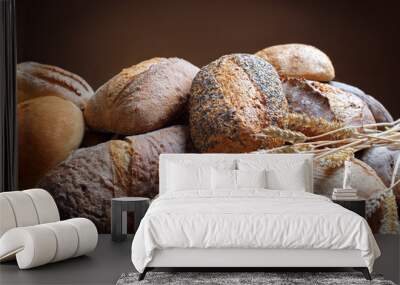 heap of fresh baked bread and wheat ears on brown background Wall mural