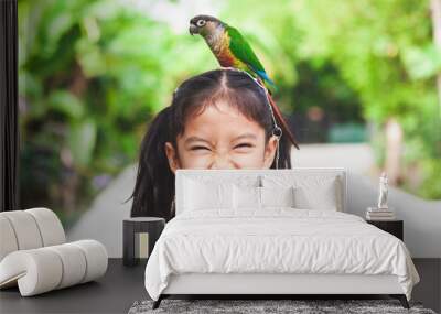 beautiful little parrot birds standing on child head. asian child girl play with her pet parrot bird Wall mural