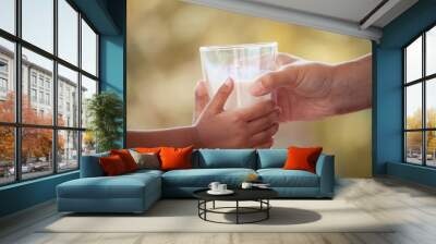 Woman hand giving glass of milk to child in vintage color tone Wall mural