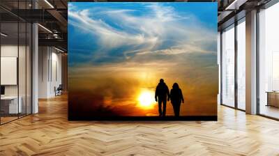 Silhouette of man and woman holding hands and walking together towards spectacular sunset Wall mural