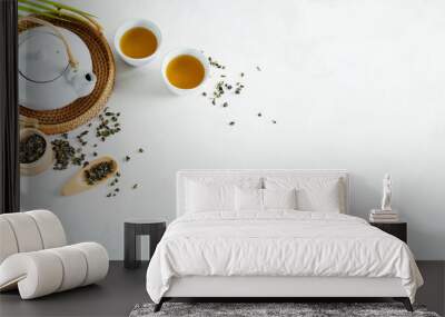 Asian tea concept, two white cups of tea and teapot surrounded with green dry tea  with space for a text on light background. Wide banner. Wall mural