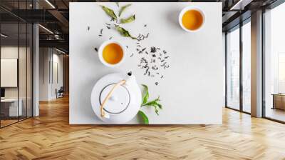 Tea concept with two white cups of tea and teapot surrounded with fresh green tea leaves and dry leaves,  top view composition on concrete background with copy space. Wall mural