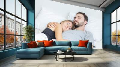 Young cute couple hug and sleep together in bed Wall mural