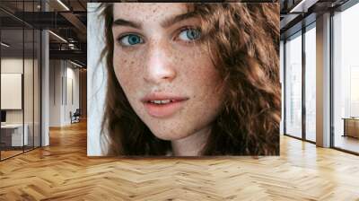 Beautiful Freckles young woman close up portrait. Attractive model with beautiful blue eyes and ginger curly hair Wall mural