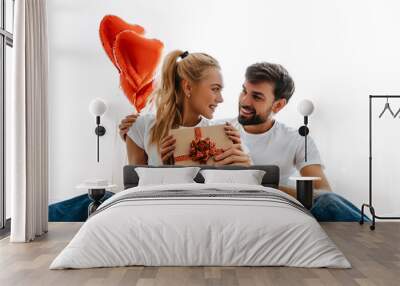 Couple. Love. Valentine's day. Woman is holding a gift box and looking at her man, both are smiling Wall mural