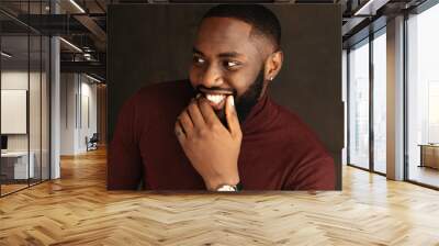 Man portrait. Style. Handsome Afro American guy in wine-colored sweatshirt is smiling, on a dark background Wall mural