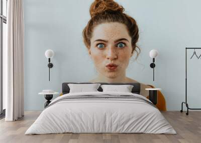 Woman portrait. Style. Beautiful blue eyed girl with freckles is pouting lips at camera, on a white background Wall mural