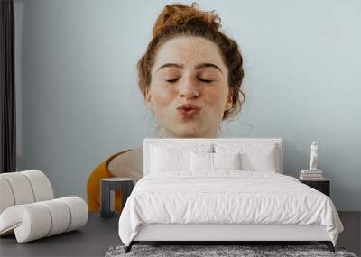 Woman portrait. Style. Beautiful girl with freckles is pouting lips at camera, on a white background Wall mural