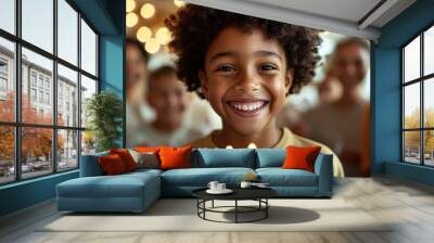 A cheerful child with a wide smile stands near a birthday cake with bright candles, surrounded by family and friends, enjoying a happy birthday celebration. Wall mural