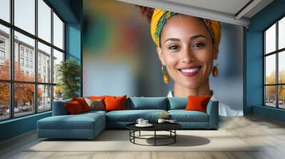 A cheerful woman wearing a colorful head wrap and white shirt smiles radiantly, set against a backdrop of bright colors and vibrant energy in a casual space. Wall mural