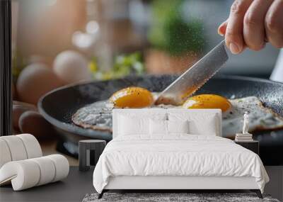 A close-up of two perfectly cooked sunny-side-up eggs being seasoned with pepper, set on a dark non-stick frying pan, illustrating the art of breakfast preparation. Wall mural