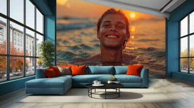 A happy young male swimming in the ocean with a sunset backdrop, water glistening on his skin Wall mural