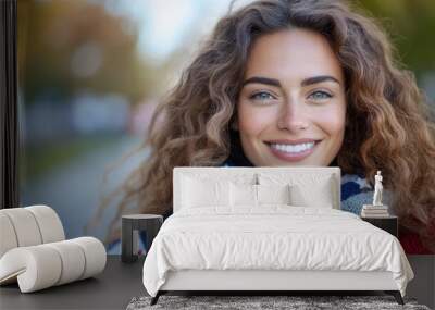 A joyful woman with curly hair stands outdoors wrapped in an American flag. Her wide, welcoming smile and bright eyes embody happiness and patriotism. Wall mural