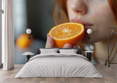 A person's hand is shown holding a half orange up, creating a vibrant contrast and focus on the freshness of the fruit Wall mural