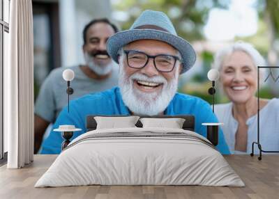 A senior man with a white beard and glasses smiles joyfully at the camera, with two friends standing in the background, capturing the essence of friendship and happiness. Wall mural