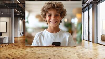 A vibrant image showcasing a child with curly hair wearing a white t-shirt and holding a smartphone, set in a lively indoor environment filled with plants and modern decor. Wall mural