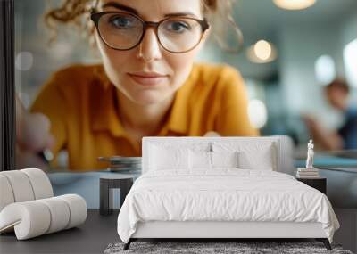 A woman intensely focuses on counting coins beside papers and charts, showcasing precision in managing finances and data analysis within a modern office environment. Wall mural