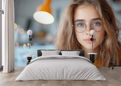 A young woman with glasses intently reads papers at her desk under a bright lamp, in a stylish and modern home environment, conveying focus and determination. Wall mural