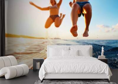 An energetic and joyful moment of two friends leaping into the water together from a boat, against the backdrop of a beautiful sunset, emphasizing fun and friendship. Wall mural