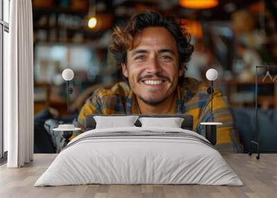 An exuberant male with a charismatic smile poses at a café, with blurred people and interior in the background Wall mural