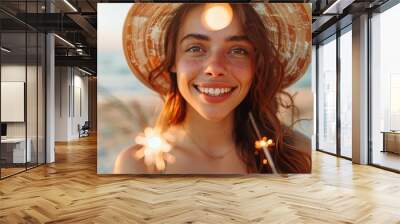 Cheerful young woman with sparklers enjoys the beach sunset, sporting an elegant straw hat and vibrant smile Wall mural