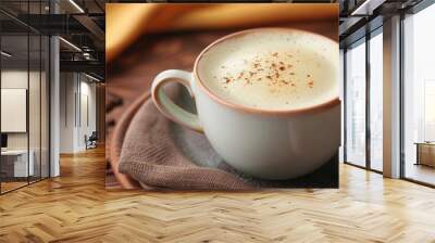 Delicious cappuccino with frothy foam, coffee bean topping, and a cup handle visible, against a wooden background Wall mural